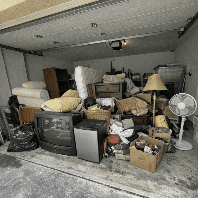Pile of old furniture and household items in a garage ready for junk removal before a move.