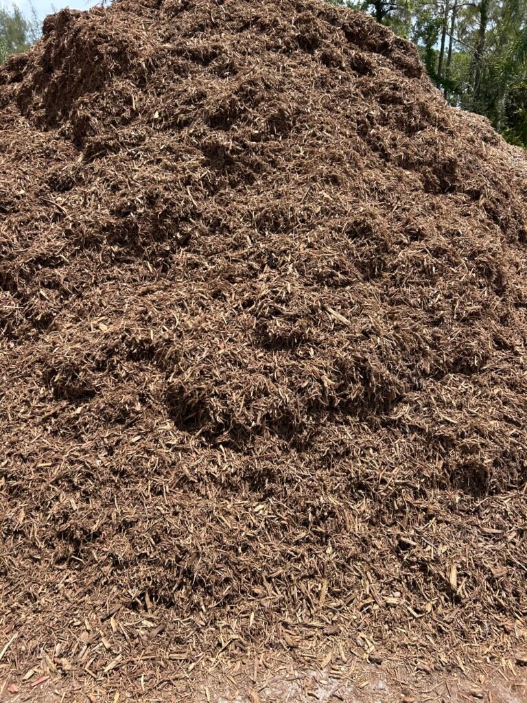 Fresh mulch installation in a Palm Beach County landscape bed by On-Call Hauler.